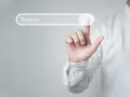 Palec wskazujący dotyka paska wyszukiwania, symbolizując wyszukiwanie informacji i dane strukturalne Google.