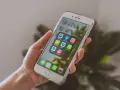Dłoń trzyma smartfon z ikonami aplikacji społecznościowych. Chcesz wiedzieć, jak promować post na Instagramie? Zacznij od tych narzędzi!