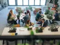 Ludzie dyskutują przy stołach w nowoczesnym biurze. To miejsce, gdzie można znaleźć odpowiedzi na pytania, jak na Quora.