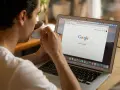 Mężczyzna popija kawę, przeglądając stronę Google na laptopie. Dyskutuje o aktualizacjach algorytmu Google.