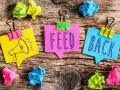 Kolorowe karteczki z napisem "FEED BACK" i rysunkiem megafonu. Świetne feedback przykłady!