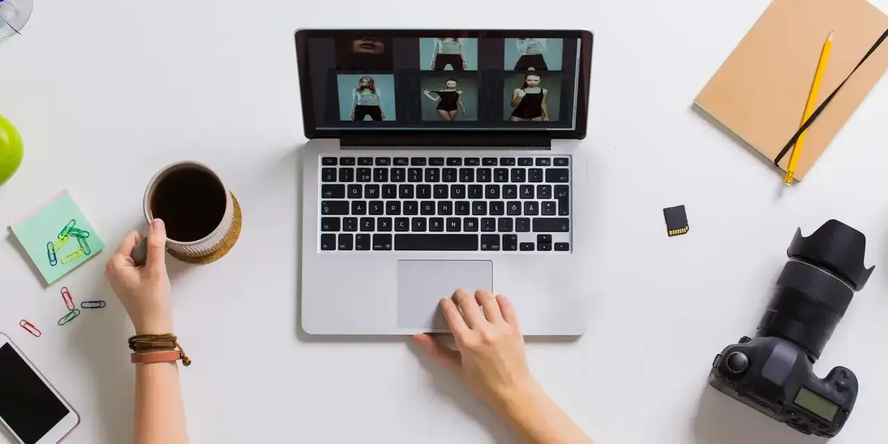Praca blogera: przeglądanie zdjęć na laptopie, kawa, aparat i notatnik.