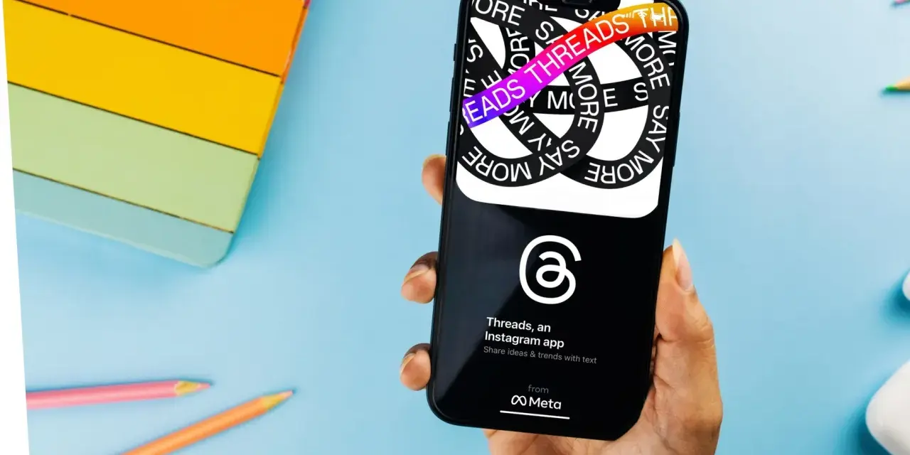 Dłoń trzyma smartfon z aplikacją Threads, która pozwala dzielić się pomysłami i trendami.