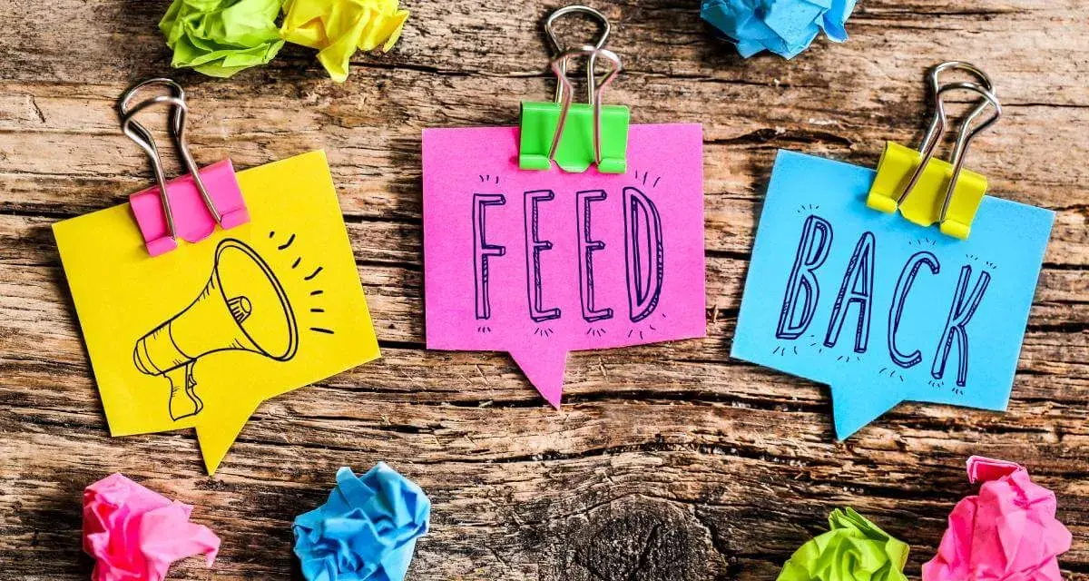 Kolorowe karteczki z napisem "FEED BACK" i rysunkiem megafonu. Świetne feedback przykłady!
