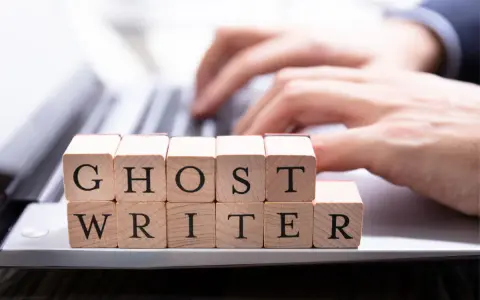 Drewniane klocki z literami tworzą napis "GHOST WRITER". Kto to taki? To pisarz, który tworzy teksty dla kogoś innego.