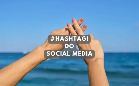 Dwie dłonie tworzą znak #. Tekst: #HASHTAGI DO SOCIAL MEDIA. Idealne gotowe hashtagi na wakacje!