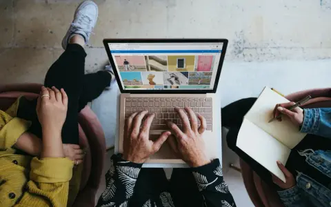 Zespół marketingu realizuje zadania: ktoś pisze na laptopie, ktoś notuje w zeszycie, tworząc kreatywną kampanię.