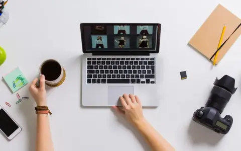 Praca blogera: przeglądanie zdjęć na laptopie, kawa, aparat i notatnik.