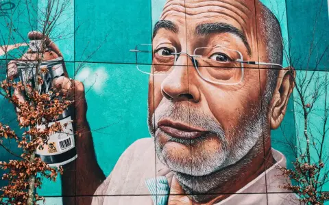 Mural przedstawiający mężczyznę z wąsami i okularami, trzymającego puszkę farby. To przykład odważnego guerrilla marketing.