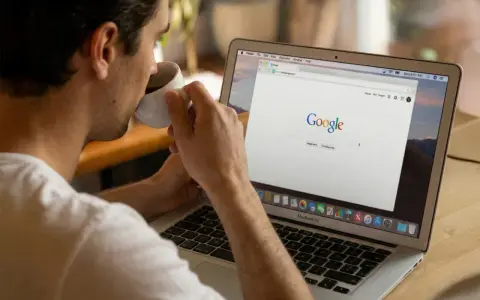 Mężczyzna popija kawę, przeglądając stronę Google na laptopie. Dyskutuje o aktualizacjach algorytmu Google.