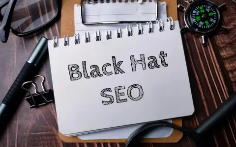 Notatnik z napisem "Black Hat SEO", okulary, długopis i kompas na drewnianym tle.