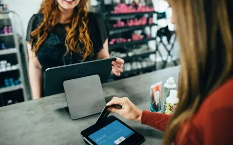 Klientka płaci kartą w sklepie, co jest przykładem, jak działa omnichannel – płynne połączenie różnych kanałów sprzedaży.