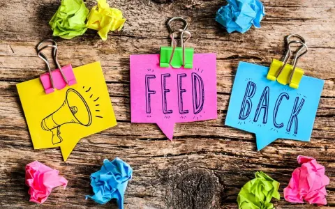 Kolorowe karteczki z napisem "FEED BACK" i rysunkiem megafonu. Świetne feedback przykłady!