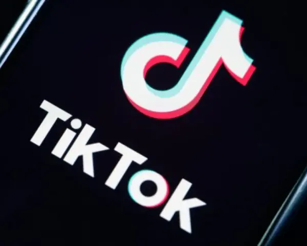 Logo TikToka na czarnym tle. Aplikacja zyskała popularność w 2018 roku, choć jej początki sięgają 2016.