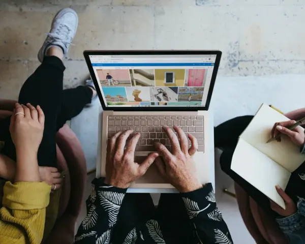Zespół marketingu realizuje zadania: ktoś pisze na laptopie, ktoś notuje w zeszycie, tworząc kreatywną kampanię.