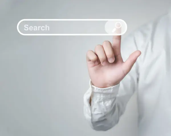Palec wskazujący dotyka paska wyszukiwania, symbolizując wyszukiwanie informacji i dane strukturalne Google.
