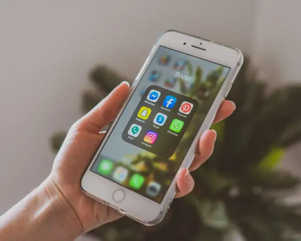 Dłoń trzyma smartfon z ikonami aplikacji społecznościowych. Chcesz wiedzieć, jak promować post na Instagramie? Zacznij od tych narzędzi!