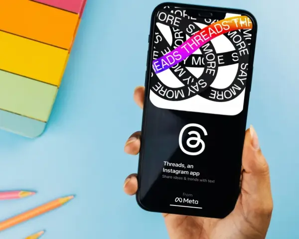 Dłoń trzyma smartfon z aplikacją Threads, która pozwala dzielić się pomysłami i trendami.