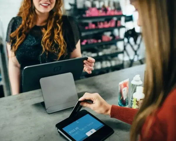 Klientka płaci kartą w sklepie, co jest przykładem, jak działa omnichannel – płynne połączenie różnych kanałów sprzedaży.