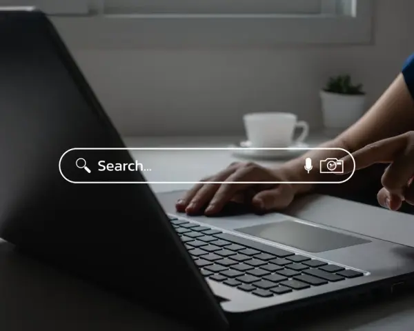 Osoba wpisuje zapytanie w wyszukiwarkę na laptopie, szukając najpopularniejszych wyszukiwarek internetowych w Polsce.
