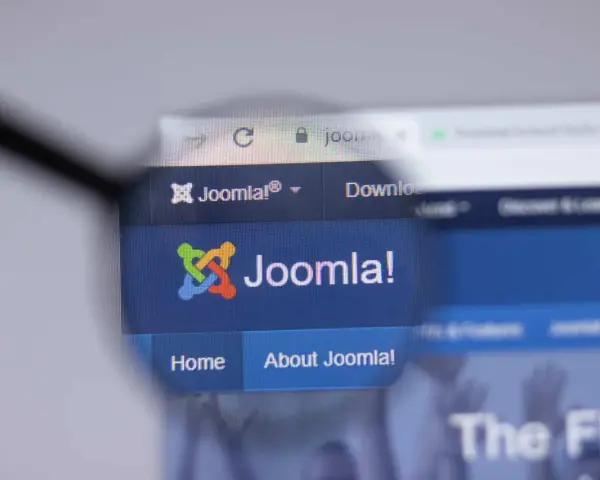 Lupa powiększa logo i nazwę Joomla!, systemu zarządzania treścią. Dowiedz się, joomla co to jest i jak działa.
