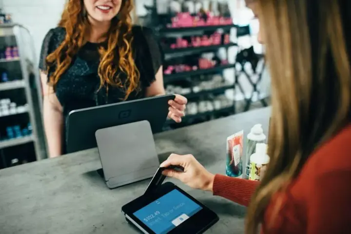 Klientka płaci kartą w sklepie, co jest przykładem, jak działa omnichannel – płynne połączenie różnych kanałów sprzedaży.