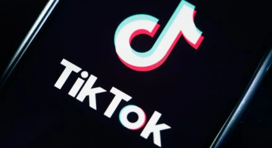 Logo TikToka na czarnym tle. Aplikacja zyskała popularność w 2018 roku, choć jej początki sięgają 2016.