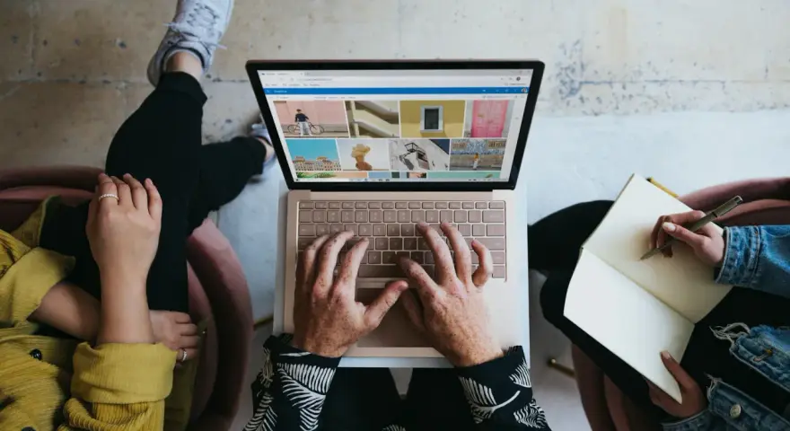 Zespół marketingu realizuje zadania: ktoś pisze na laptopie, ktoś notuje w zeszycie, tworząc kreatywną kampanię.