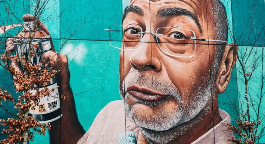 Mural przedstawiający mężczyznę z wąsami i okularami, trzymającego puszkę farby. To przykład odważnego guerrilla marketing.