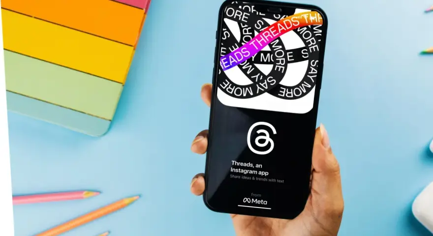 Dłoń trzyma smartfon z aplikacją Threads, która pozwala dzielić się pomysłami i trendami.