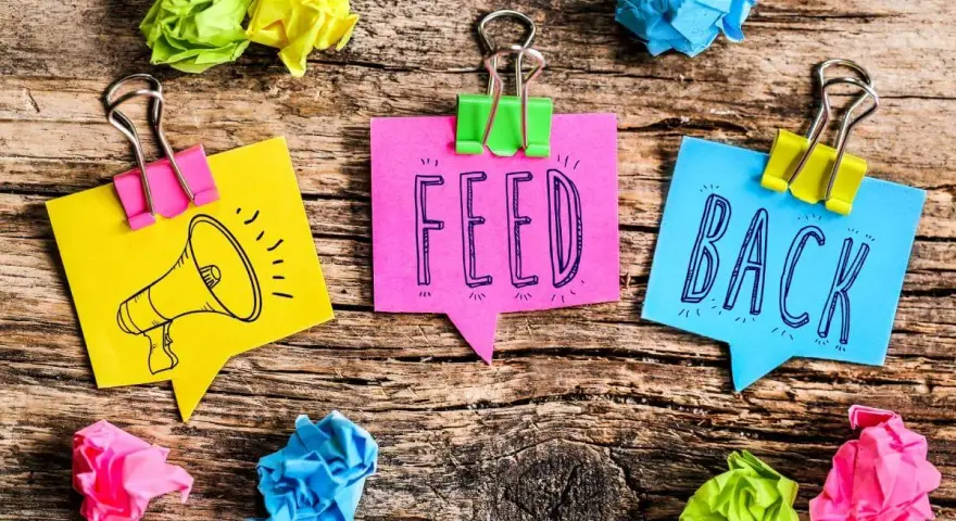 Kolorowe karteczki z napisem "FEED BACK" i rysunkiem megafonu. Świetne feedback przykłady!