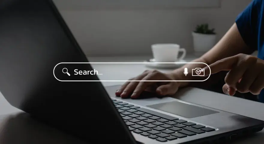 Osoba wpisuje zapytanie w wyszukiwarkę na laptopie, szukając najpopularniejszych wyszukiwarek internetowych w Polsce.